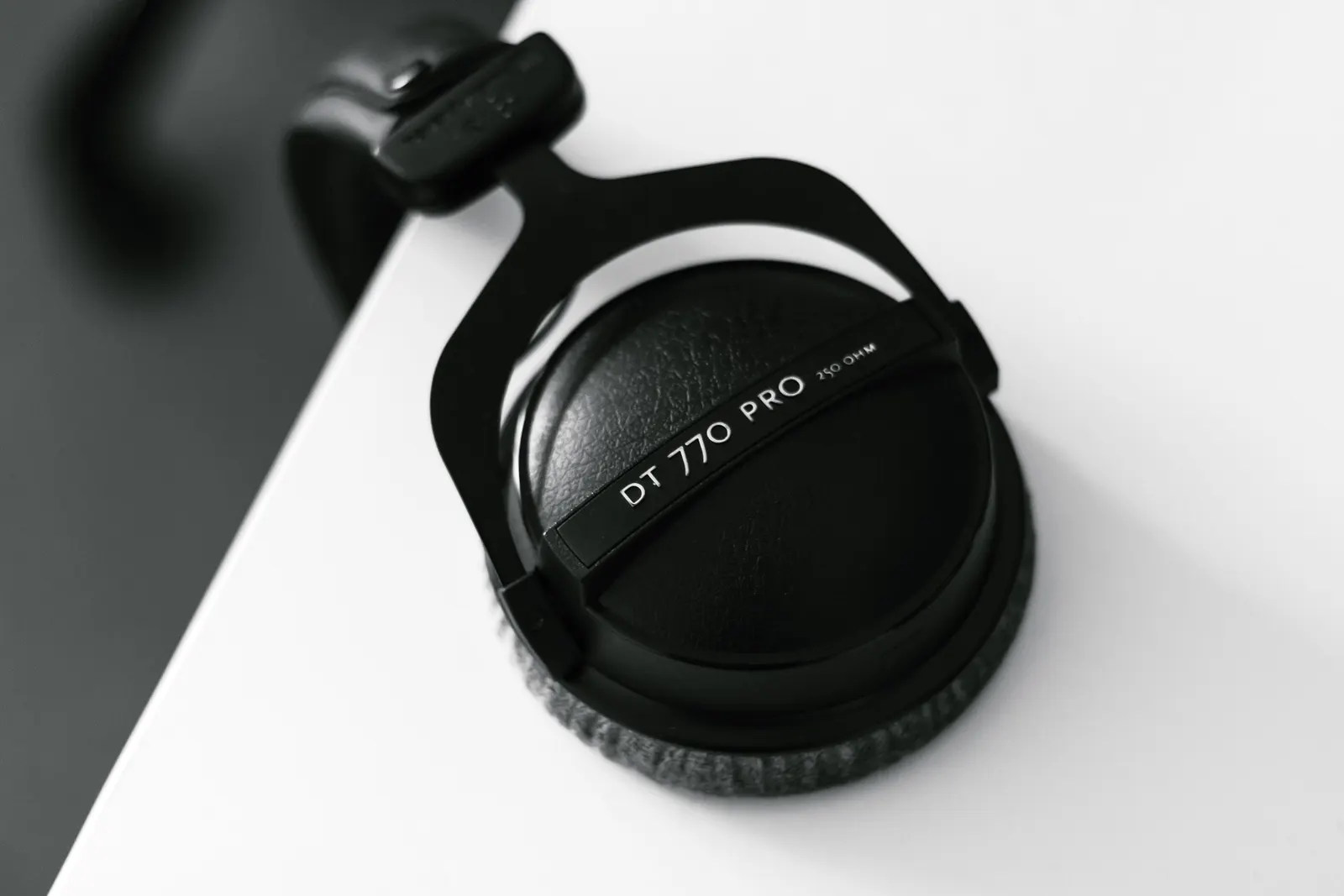 Black over-ear studio headphones resting on the edge of a white desk