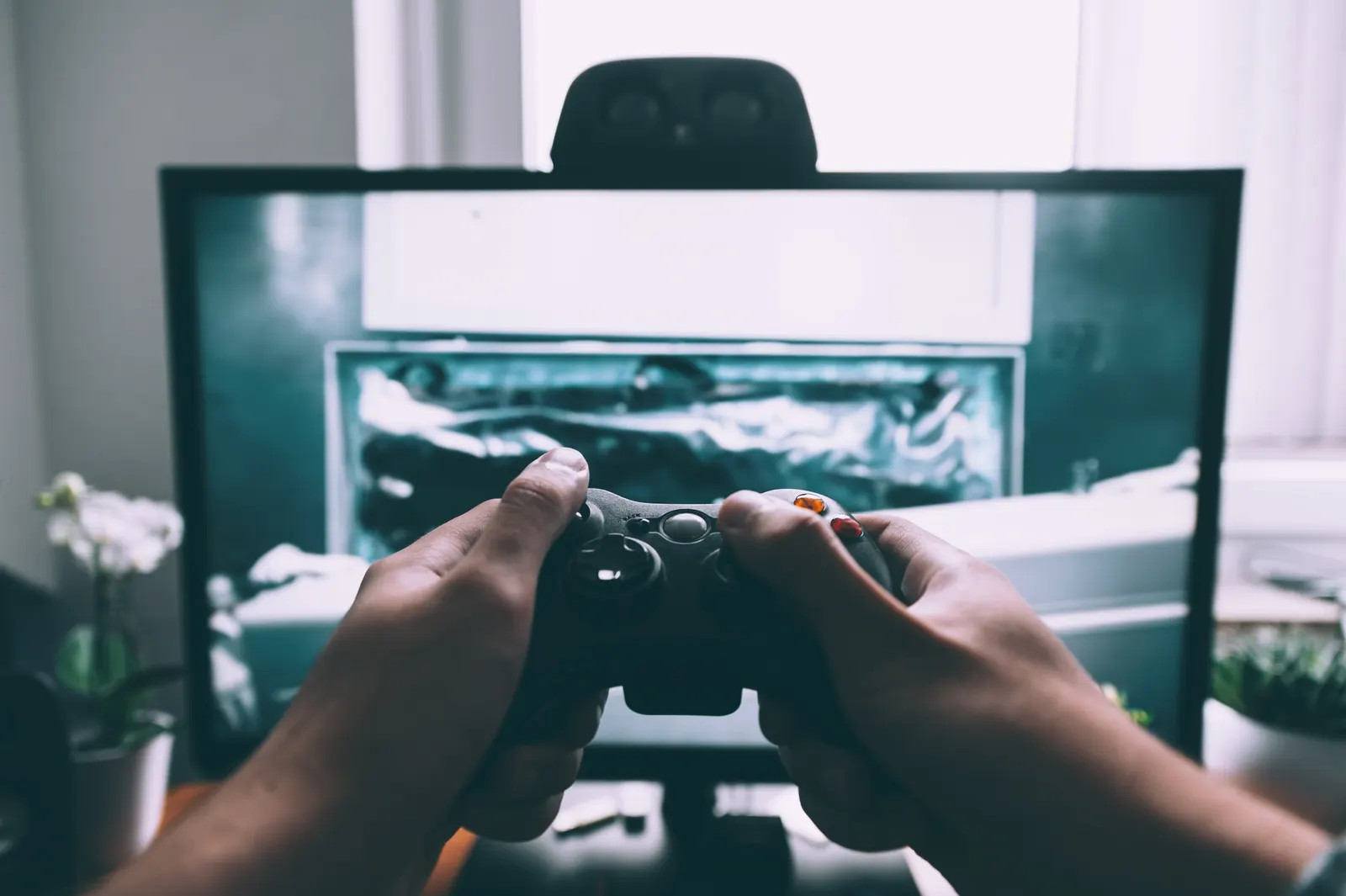 Hands holding a game controller in front of a television screen
