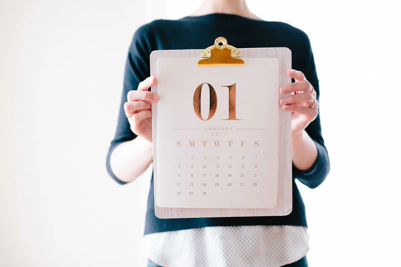 Person holding a clipboard calendar showing the number 01 for January